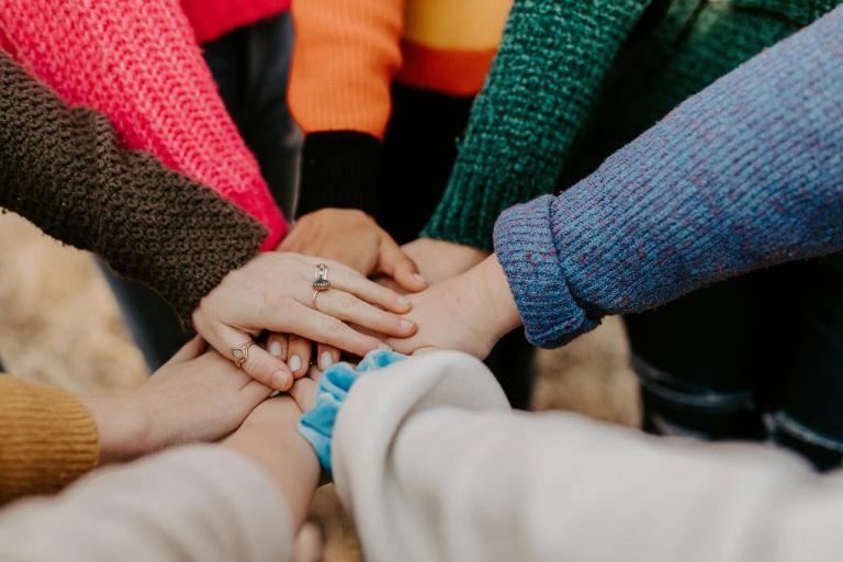 A group of people with their hands on top of each other.